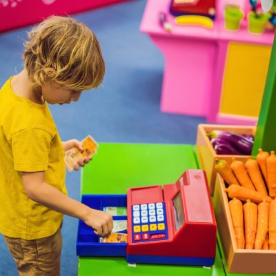The boy plays with the children's cash register.