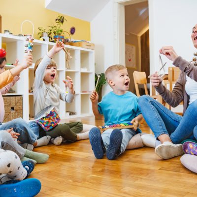 Teacher with children in a Kindergarten Classroom. Healthy learning environment. Kindergarten teacher, building relationships with the kids. Cheerful preschool children