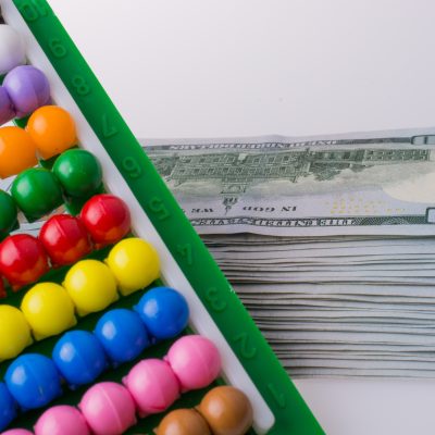 American dollar banknotes by the side of a colorful abacus on white background